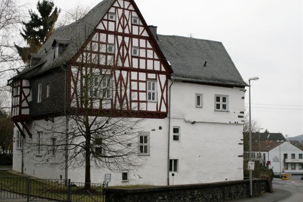 Das Hofhaus Langendernbach: weiß verputzter Steinbau mit dunkelrotem Fachwerkobergeschoss.